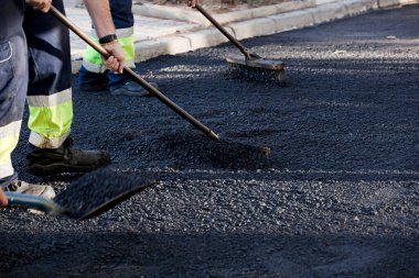 Şehirdeki asfalt araçlar ve üniformalarla çalışan operatörler