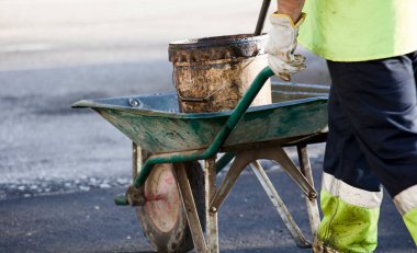 Asfalt aletli el kamyonu, üniformalı operatör.