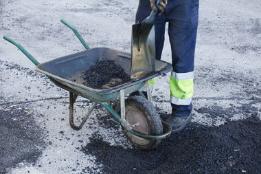 El arabası operatöründeki asfalt üniformayla karışımı hazırlar