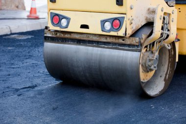 İnşaat alanında yol silindiri ve asfalt kaldırım makinesi, sıcak beton ve dumanla