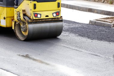 İnşaat alanında yol silindiri ve asfalt kaldırım makinesi, sıcak beton ve dumanla