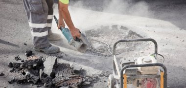 Asfalt işçisinin ellerindeki radyal toprağı ve taşınabilir elektrik jeneratörünü keser.
