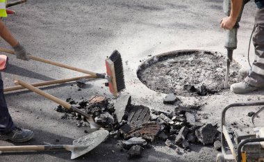 İki üniformalı işçi yolda çalışıyor.