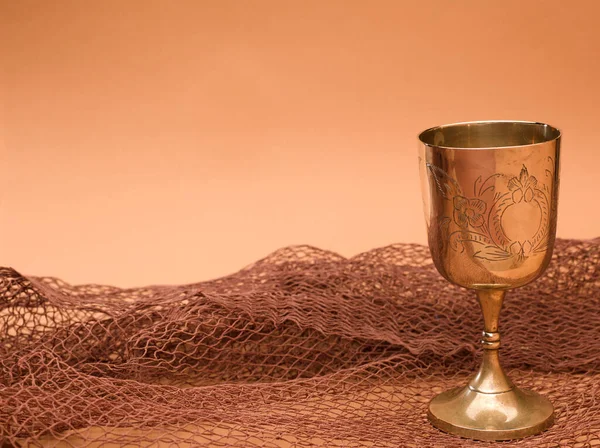 gold chalice with fishing net on brown background