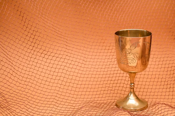 gold chalice with fishing net on brown background