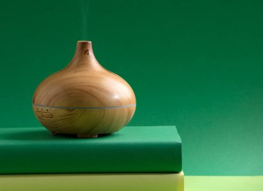 wood fragrance on the table, with natural oils essence vapor, man hands with books various greenish tones and green background