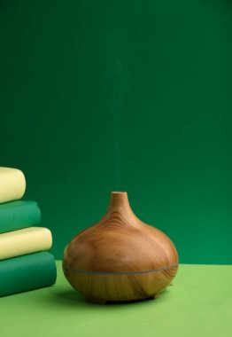 wood fragrance on the table, with natural oils essence vapor, man hands with books various greenish tones and green background