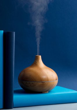 wood fragrance on the desk table with natural oils essence vapor, with blue and teal colored books