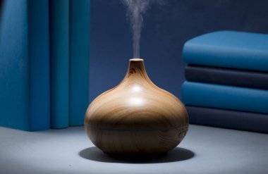 wood fragrance on the table with natural oils essence vapor, with blue and teal colored books