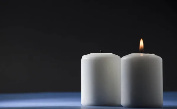 两只蜡烛 分别放在蓝色桌子上和蓝色桌子上 背景是黑色的 — 图库照片