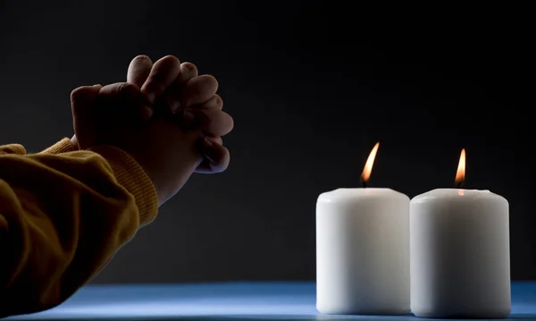 Boy Yellow Jumper Crossed Hands Prays Burning Candles Blue Table — Stock Photo, Image