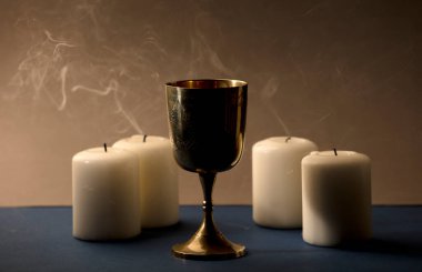 4 sönmüş mumlu, dumanlı, kahverengi arka planlı Altın Hıristiyan kadehi.