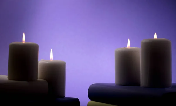 candles and books with purple background, space central for text