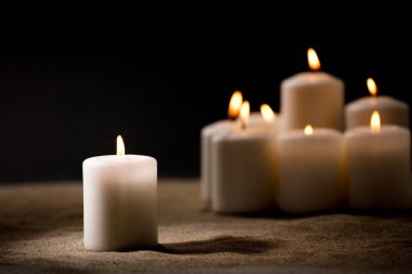 Zorbalık kavramı, yanan mumlardan oluşan bir grup, siyah gece arkaplanlı kum üzerinde