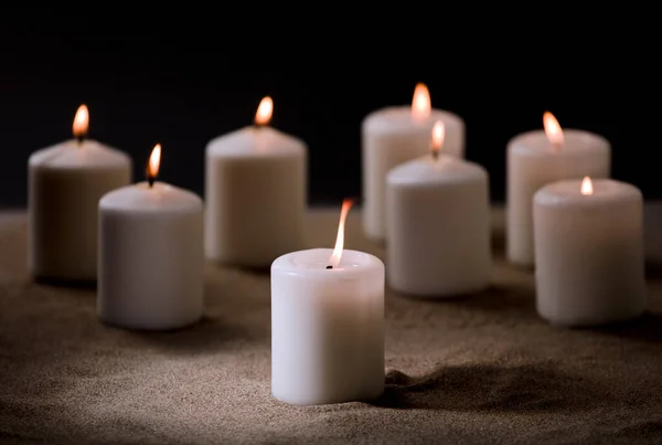 由一组点燃的蜡烛组成 在沙地上 有漆黑的夜晚背景 — 图库照片