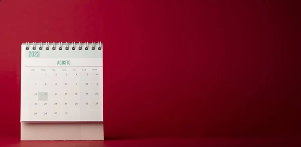 Desk calendar for the month of August 2023 with wine red background