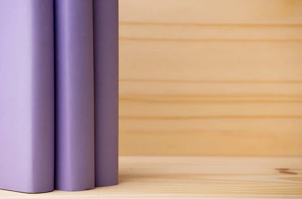 lilac books on natural wooden bookshelf, space for text