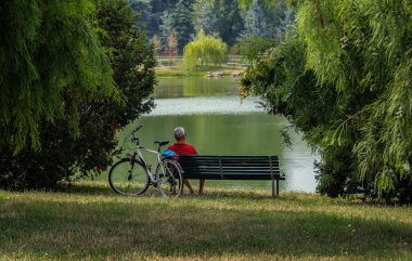 Parkta bankta oturan bir adam göl / modele bakıp tanınmaz hale gelir.