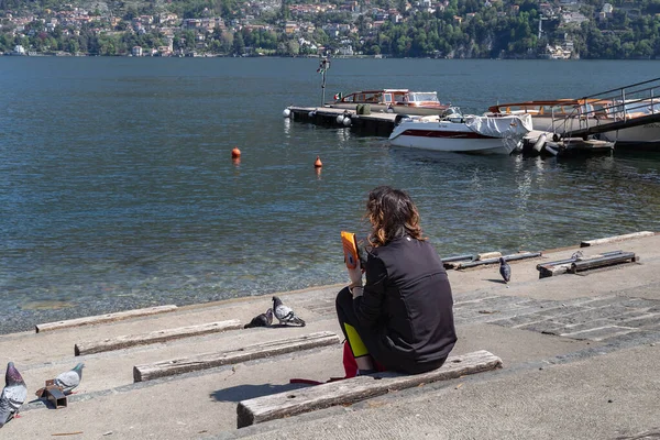 Genç bir kadın gölün merdivenlerinde oturuyor ve o da manzaraya bakıyor. Manken tanınmaz halde.