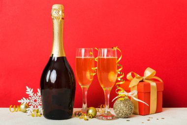 Champagne bottle with confetti, glasses and christmas decor on colored holiday background. Flat lay New Year decorations.