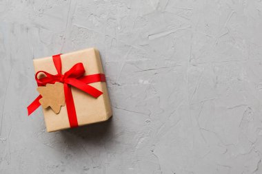 wrapped christmas or other holiday handmade present in paper with colored ribbon. Present box, decoration of gift on colourfull table, top view with copy space.