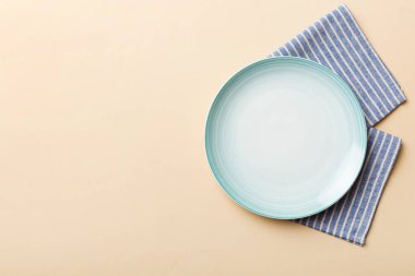 Renkli arkaplanda üst görünüm yiyecek için mavi tabak üzerinde boş. Tasarımınız için boşluk olan peçeteye boş tabak.