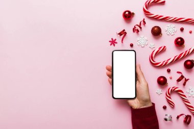 Mesaj atmak için yeri olan bir Noel modeli. Noel reklamı, uygulama şablonu. Masa arkasında boş ekran olan el ele tutuşan telefon. Mutlu yıllar ve Xmas Flat.
