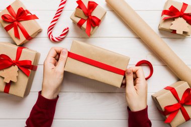 Kadınlar Noel tatili için sürpriz hediyeler hazırlıyor. İş yerinde el aletleri ve manzarayla oturuyor. Renkli masada Noel hediyesini paketleyen kadın..