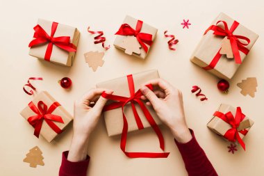 Kadınlar Noel tatili için sürpriz hediyeler hazırlıyor. İş yerinde el aletleri ve manzarayla oturuyor. Renkli masada Noel hediyesini paketleyen kadın..