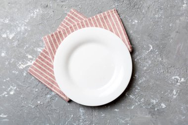 Renkli arka planda üst görünüm yiyecek için masa örtüsü üzerindeki boş yuvarlak beyaz tabak. Tasarımınız için boşluk olan peçeteye boş tabak.