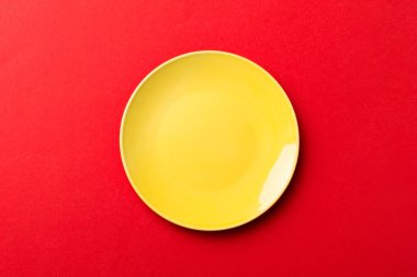 Renkli arka plan görüntüsünün üst görüntüsü yiyecek için boş yuvarlak sarı tabak. Tasarımınız için alanı olan boş tabak.