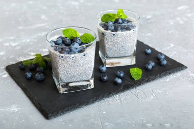 Sağlıklı kahvaltı ve chia tohumlu vanilyalı puding ve böğürtlenli masa arkası, vejetaryen gıda, diyet ve sağlık konsepti. Hindistan cevizi sütü ve yabanmersinli Chia pudingi..