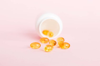 Yumuşak jel hapları ve Omega-3 yağı hap şişesinden sızıyor. Jel kapsülleri beyaz yüzey şişesi. Omega 3, multivitamin, kalsiyum, antibiyotik. Sağlığa. Dokunulmazlık.