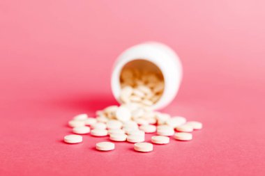 Medicine bottle and white pills spilled on a light background. Medicines and prescription pills flat lay background. White medical pills and tablets spilling out of a drug bottle.