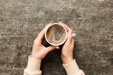 Renkli arka planda bir fincan kahve tutan minimalist stil bir kadın. Düz yerde, kapuçino bardağının üstünde. Metin için boş yer, kopyalama alanı. Kahve bağımlılığı. Üst manzara, düz uzanma.