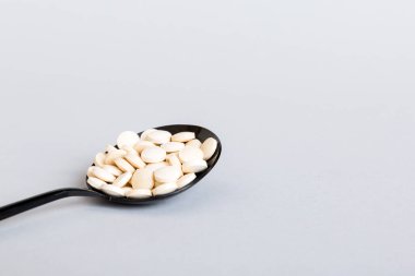 Heap of white pills on colored background. Tablets scattered on a table. Pile of red soft gelatin capsule. Vitamins and dietary supplements concept.