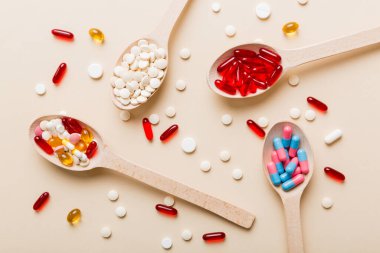 Renkli bir arka planda kaşıkta vitamin kapsülleri. Haplar sağlıklı bir yemek olarak sunuldu. Kırmızı yumuşak jel vitamin takviye kapsülleri kaşık üzerinde.