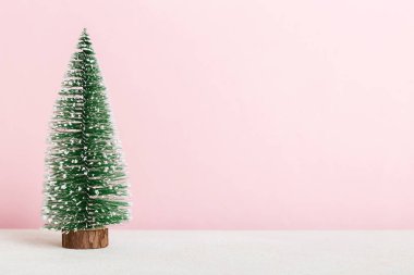 One small Christmas tree on colored background. new year decoration with copy space.