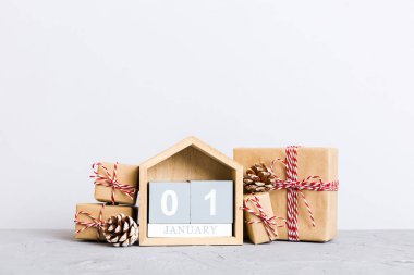 1 january. Christmas composition on colored background with a wooden calendar, with a gift box, toys, bauble copy space.