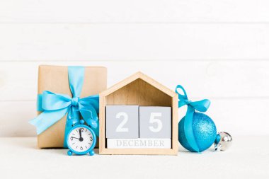 25 december. Christmas composition on colored background with a wooden calendar, with a gift box, toys, bauble copy space.