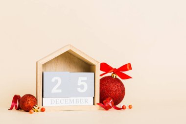 25 december. Christmas composition on colored background with a wooden calendar, with a gift box, toys, bauble copy space.