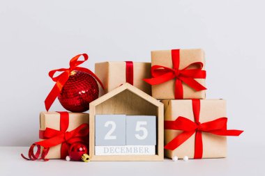 25 december. Christmas composition on colored background with a wooden calendar, with a gift box, toys, bauble copy space.