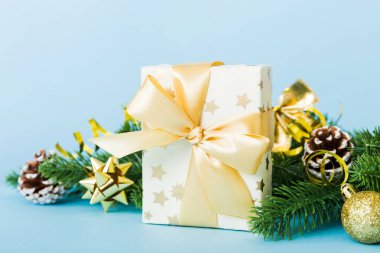 New Year Christmas mood, gift box, branches of a christmas tree, New Year decorations on a colored background.