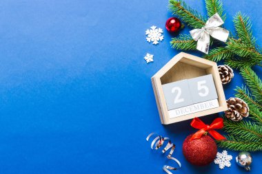 Christmas calendar 25 december. Christmas gift, fir branches, pine cones. Flat lay, top view. New Year decorations on a colored background.