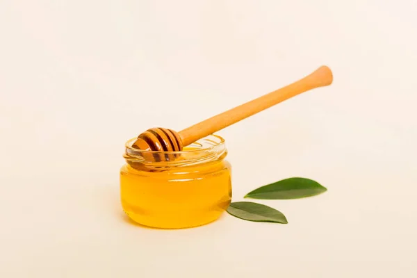 带有叶子的瓶子中的蜂蜜和带有复制文本的彩色背景色中的蜂蜜切菜 — 图库照片