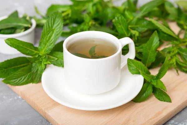 Cup of mint tea on table background. Green tea with fresh mint top view with copy space.