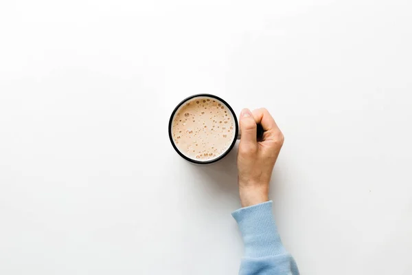 stock image Minimalistic style woman hand holding a cup of coffee on Colored background. Flat lay, top view cappuccino cup. Empty place for text, copy space. Coffee addiction. Top view, flat lay.