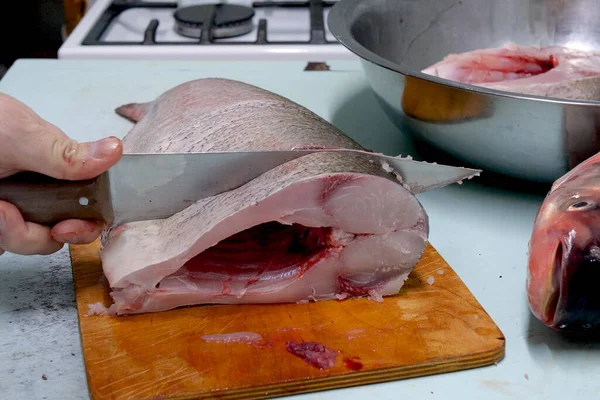 男は新鮮な銀鯉の魚を準備します ナイフでステーキに切ります 家庭料理のコンセプト — ストック写真