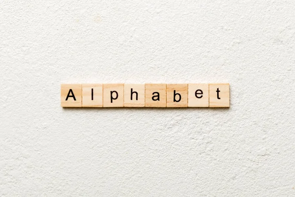 木のブロックに書かれたアルファベットの単語 デザインやコンセプトのためのセメントテーブルのアルファベットテキスト — ストック写真