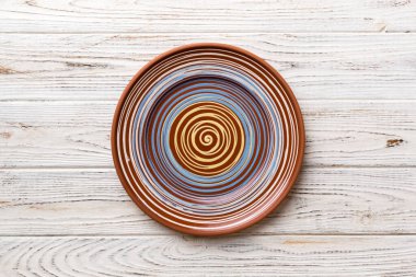 Ahşap zemindeki boş renkli tabağın üst görünümü. Tasarımın için boş boşluk.